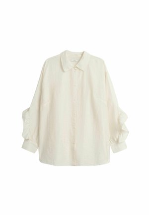 Biała, długa koszula z długim rękawem, zapinana na guziki, uszyta z fakturowanej tkaniny. Posiada klasyczny kołnierz oraz marszczone detale przy rękawach.