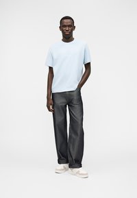 Heleroheline puuvillane T-särk ümarselja kaelusega, kombineeritud tumedate denimist laiade pükstega. Jalarõivaks valged jalanõud beežide detailidega.