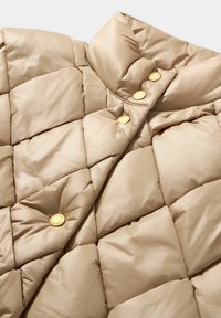 Beżowa pikowana kurtka puchowa z wysokim kołnierzem i złotymi zatrzaskami. Gładki, błyszczący materiał z przeszyciem w kształcie diamentów.