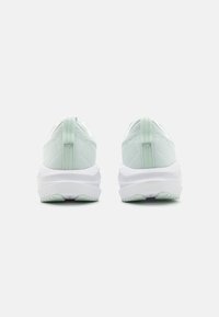 Baskets de sport vert clair avec une tige en tissu texturé, un col rembourré et une semelle intermédiaire blanche. Dispose d'une languette au talon pour un enfilage facile.