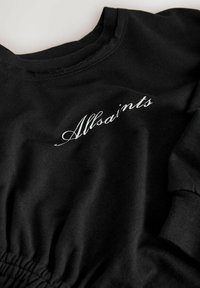 Mustmust mustrik, kus on kereosa, elastne vöökoht ja esiküljel hõbedases kursiivi kirjutuses "Allsaints".