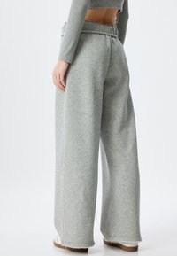Lichtgrijze joggingsbroek van zachte stof, met een elastische tailleband, een brede pijp ontwerp en rafelige zoom aan de enkels.
