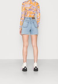 Farkkushortsit, vaaleansininen, rosoinen helma, kaksi takataskua; yhdistetty pitkähiharaiseen, moniväriseen, abstraktikuosiselle paidalle ja nilkkureihin.