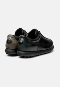 Due paia di sneakers stilose in pelle nera testurizzata con accenti in verde scuro e marrone a contrasto, esposte da dietro.