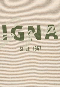 Camiseta de tela a rayas en beige claro y verde oscuro. Presenta un gran texto "SIGNO" y "DESDE 1967" en letras negritas. Textura suave.
