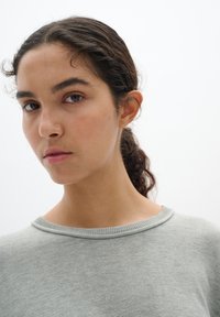 Light green, knitted sweater with a round neckline and subtle ribbed accents at the collar. Smooth texture, fitted style.
