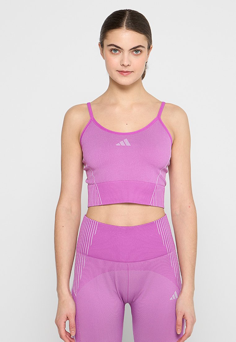 Rosa sportlicher Cropped-Top mit dünnen Trägern und enganliegendem Schnitt, mit subtilen weißen Akzenten und einem strukturierten Design für zusätzliche Details.