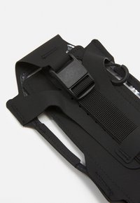 Bracciale elastico nero con strap regolabile, chiusura a fibbia e superficie liscia; progettato per trattenere gli oggetti in modo sicuro, presenta un design minimalista.