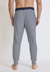 Męskie piżamowe spodnie w paski w kolorze granatowym i białym. Elastyczny pas, kieszenie boczne, zwężany krój, miękki materiał z poziomymi paskami.