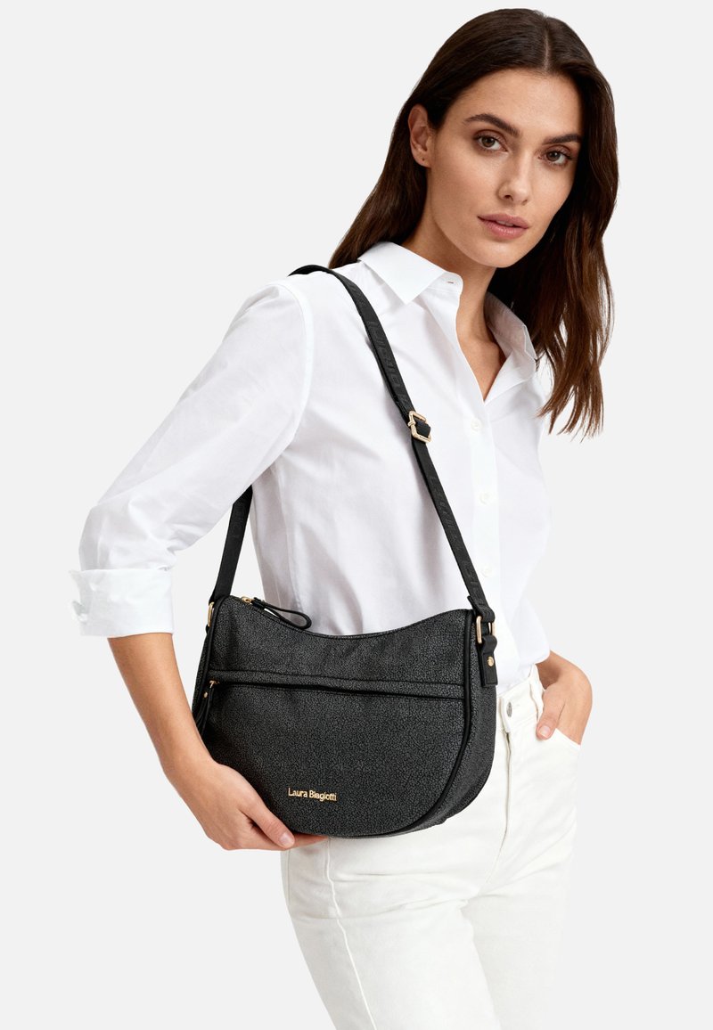 Borsa a tracolla in pelle nera texturizzata con forma curva, dotata di una tasca frontale con cerniera e dettagli in metallo dorato. Logo mostrato sul davanti.