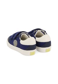 Zapatillas de color azul marino con acentos blancos, correas de velcro y un logo redondo en el costado. Cuenta con una tela texturada y una suela acolchada.