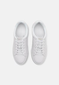 Weiße Leinenschuhe mit einer glatten Textur, weißen Schnürsenkeln und dezenten goldenen Akzenten. Sie verfügen über eine abgerundete Zehenpartie und ein niedriges Profil.