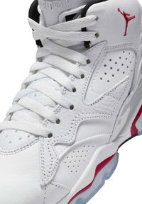Sneaker alta bianca da atletica in pelle, con dettagli perforati, lacci bianchi piatti e un logo Jordan rosso sulla linguetta.
