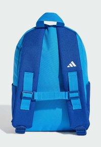 Modrý batoh s polstrovanými popruhy, nastavovacím sponou a logem Adidas na pravém ramenním popruhu na jednobarevném pozadí.