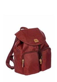 Zaino in tessuto rosso con coperchio a pattina, due tasche frontali con zip, spallacci regolabili e un dettaglio decorativo in pelle con logo.