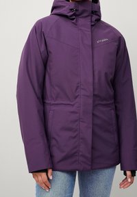 Fioletowa kurtka z kapturem o wodoodpornej powłoce, z zapięciem na zamek błyskawiczny, dwiema bocznymi kieszeniami i luźnym krojem. Gładka faktura i minimalistyczny design.