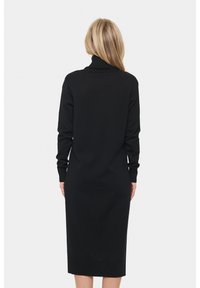 Černé pletené šaty s rolákem, dlouhými rukávy a přiléhavým střihem. Hladká textura a délka ke kolenům.