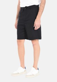 Pantaloni corti neri in cotone, con una vestibilità dritta, tasche frontali e una vita con chiusura a bottone e cordino.