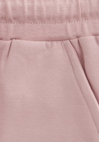 Ljusrosa bomullstyg med en strukturerad midjeband, med sydda sömmar och en veckdetalj. Mjuk, avslappnad design som är lämplig för vardagsbruk.