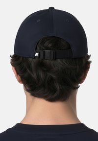 Personne vue de dos portant une casquette de baseball réglable bleu marine avec des cheveux foncés visibles sous la sangle.