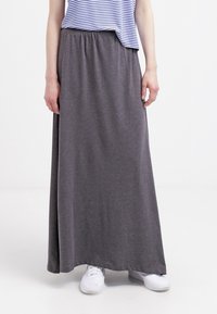 Grauer Maxirock mit elastischem Bund, aus weichem Stoff gefertigt. Kombiniert mit einem gestreiften Oberteil und weißen Sneakers. Einfaches und lässiges Design.