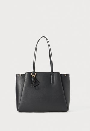 Schwarze Leder-Shopper-Tasche mit zwei langen Griffen und einem kleinen, dreieckigen Schlüsselanhänger vor einem einfarbigen, hellen Hintergrund.