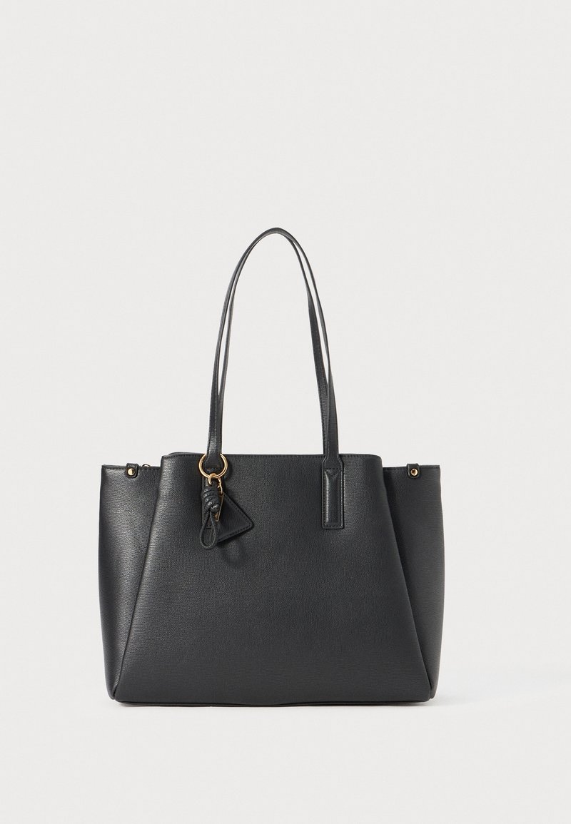 Sac cabas en cuir noir avec deux longues anses et un petit porte-clés triangulaire attaché, sur un fond clair uni.