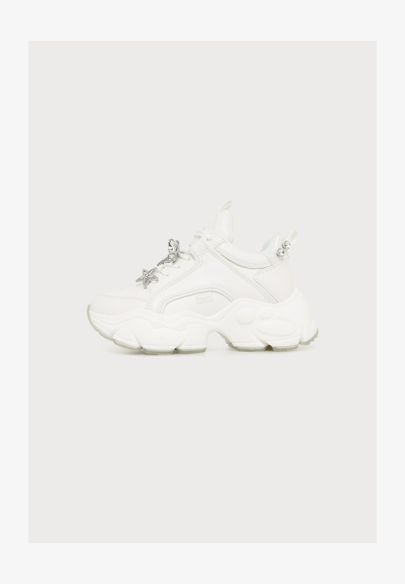 Λευκό chunky sneaker με παχιά σόλα και ασημένιο γούρι σε σχήμα αστέρι στα κορδόνια, σε ανοιχτό φόντο.