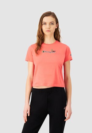 Korallfarvet cropped t-shirt lavet af bomuld, med rund hals, korte ærmer og et trykt logo med et smilende ansigt designet på brystet.