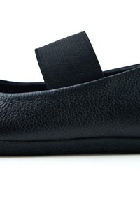 Zapato plano de cuero negro con una superficie texturizada. Presenta una correa elástica en la parte superior para un ajuste seguro y una suela flexible.