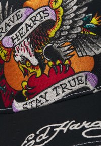 Schwarze Kappe mit lebendiger, detaillierter Stickerei eines Adlers, eines Herzens und Schriftzug "Brave Hearts Stay True!" mit mehrfarbigen Akzenten.