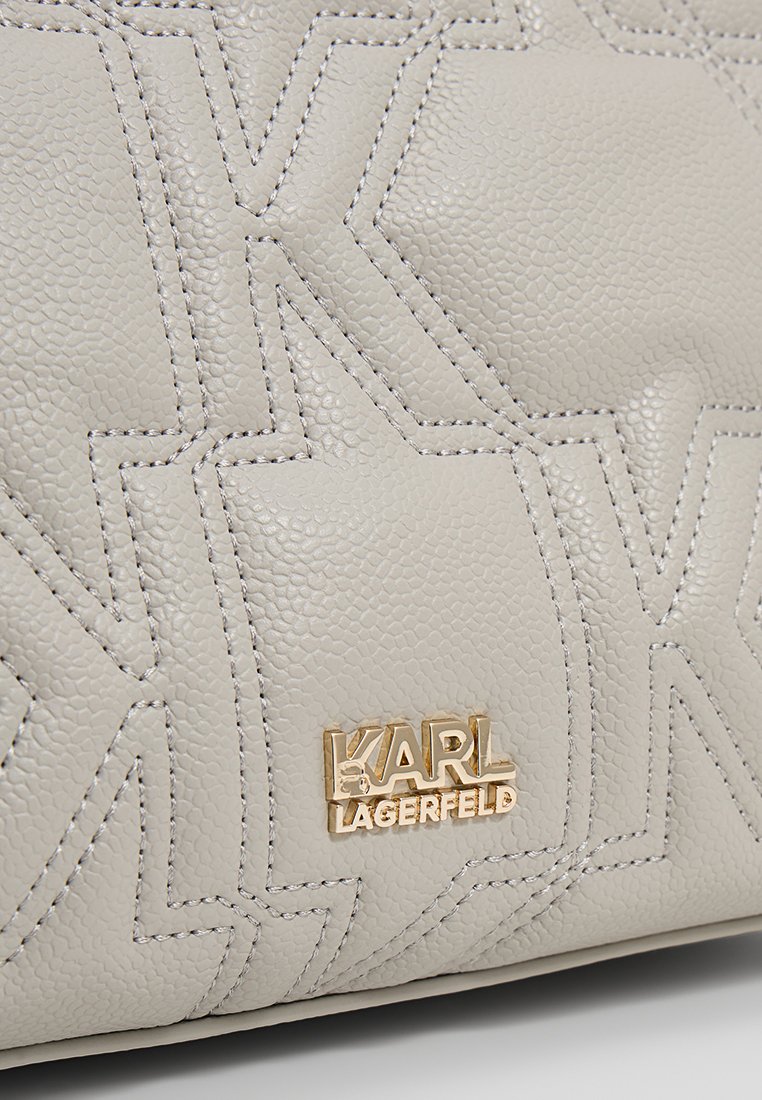 Hellgraue, strukturierte Lederhandtasche mit geprägten "K"-Motiven und goldfarbener "KARL LAGERFELD"-Logoplatte auf der Vorderseite.