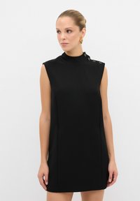 Vestido negro sin mangas con cuello alto, diseño estructurado y paneles laterales; cuenta con botones decorativos en el hombro. Textura suave.
