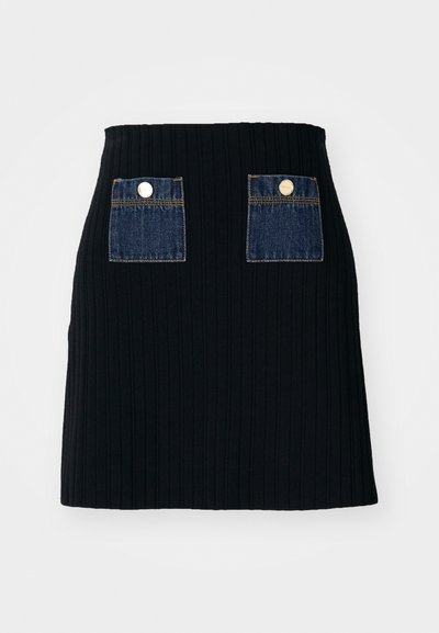 Mini-jupe noire côtelée avec taille cintrée, dotée de deux poches en denim bleu à l'avant avec des accents de boutons argentés.