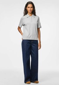 Pilkos spalvos polo marškiniai su trumpomis rankovėmis ir klasikiniu apykakle, derinami su plačiomis tamsiai mėlynomis džinsomis ir šviesiai rudos spalvos šlepetėmis.