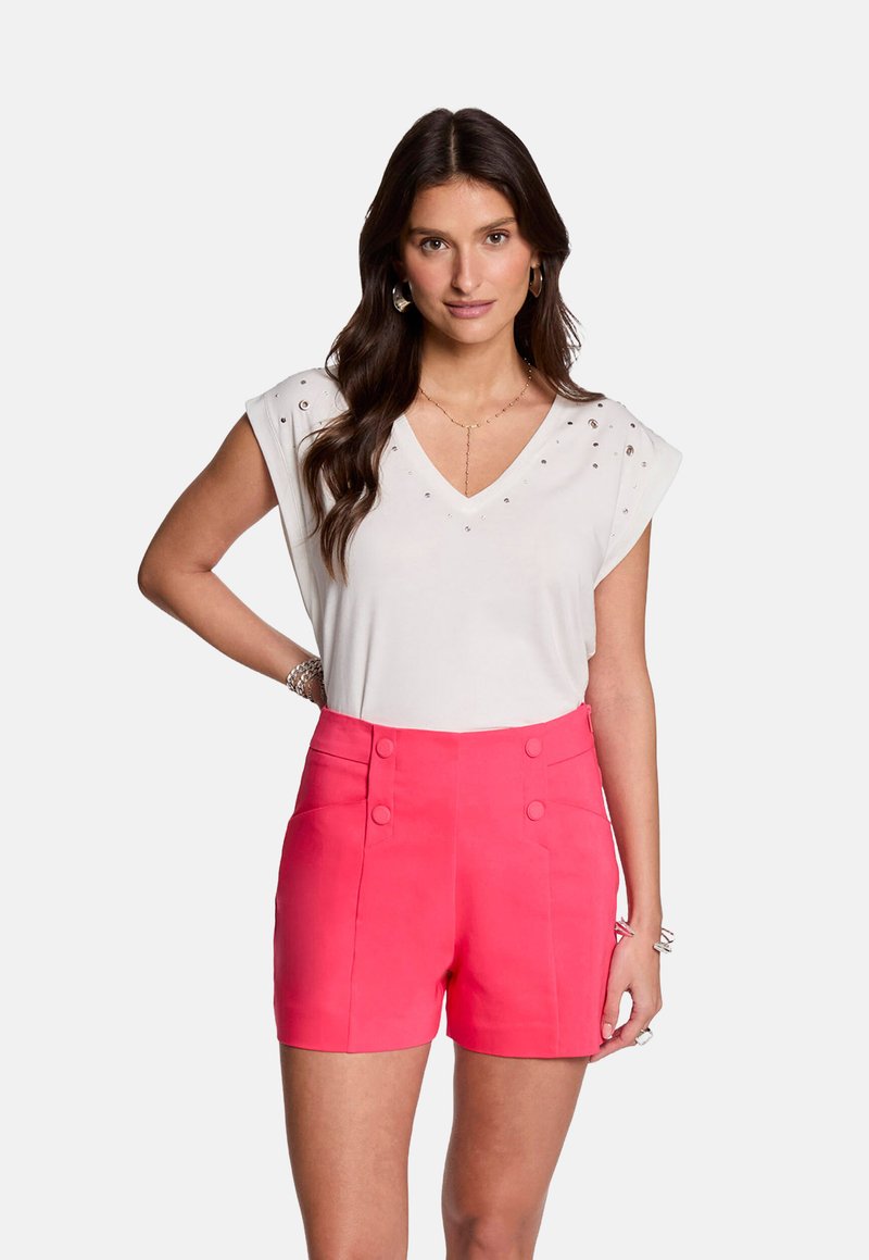 Witte v-hals top met korte mouwen en studs, gecombineerd met hoog gewaisted fuchsia tailleurs korte broek met knoopdetails en zijzakken.