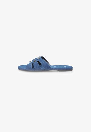 Denim slide sandals featuring a cross-strap design, blue fabric upper, and circular decorative accents on the straps. Flat sole.