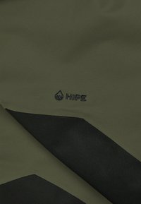 Olijfgroene stof met een gladde textuur heeft een zwart geometrisch ontwerp en een klein geborduurd "HIPE" logo.