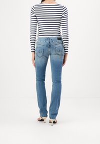 Blauwe denim jeans met een slim fit, voorzien van achterzakken, een vervaagde textuur en een middelhoge taille, gecombineerd met een gestreept shirt met lange mouwen.