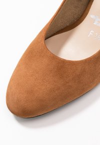 Escarpin en suède marron avec un bout rond et une doublure intérieure lisse. Présente un design classique et une texture douce.