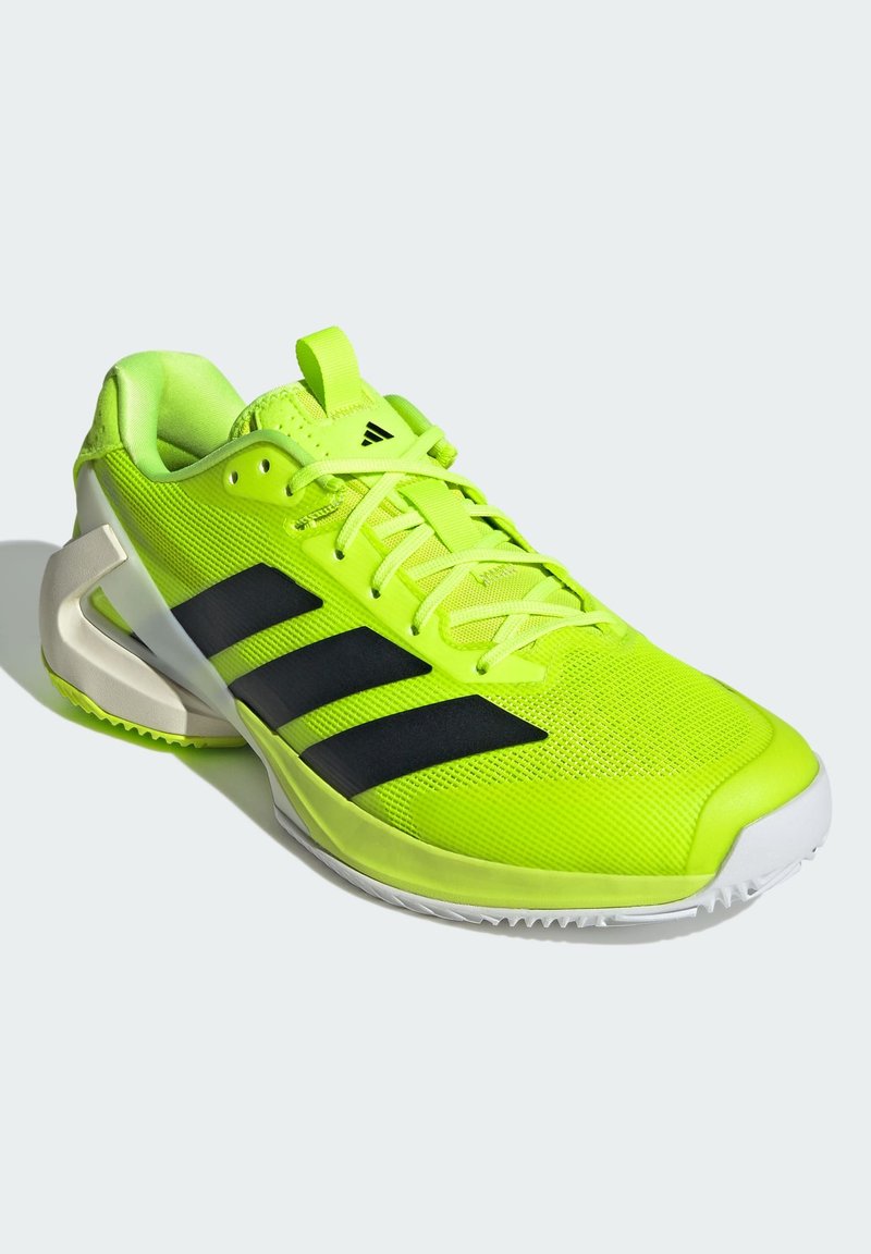 Chaussure de sport jaune néon avec des rayures noires, tige en maille, col rembourré et semelle blanche avec un motif de grip texturé.