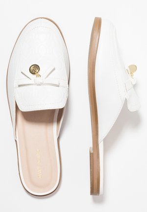 Mocassini slip-on in pelle bianca con suole color cuoio, fiocco decorativo e dettaglio medaglione dorato, mostrati da viste dall'alto e di lato.