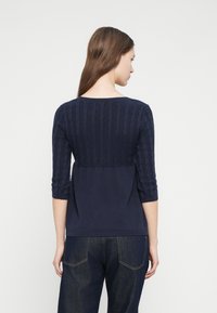 Πουλόβερ σε ναυτικό μπλε με μανίκια τριών τετάρτων, με υφή πλεκτού σχεδίου καλώδιου στην πλάτη, λείο μπροστινό μέρος και ριμπ τελείωμα.