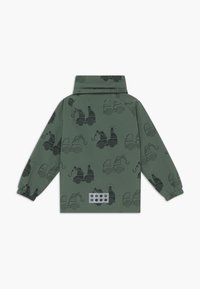 Grüne wasserdichte Jacke mit schwarzen Lkw-Mustern, hohem Kragen, elastischen Bündchen und einem reflektierenden Patch mit kreisförmigen Ausschnitten.