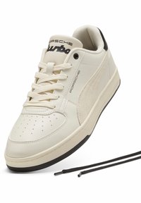 Hvide lædersneakers med perforeret tå, rund form og sorte accenter. Har snørebånd og branding på tungen og siden.