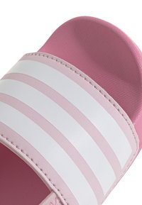 Infradito rosa con tomaia testurizzata, tre strisce orizzontali bianche e una soletta liscia con dettagli cuciti lungo il bordo.