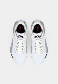 Balti un pelēki Air Jordan kedu pāris ar melniem iekšējiem zolēm, uz kuru ir sarkanais Jumpman logo, skatīti no augšas uz baltas fona.