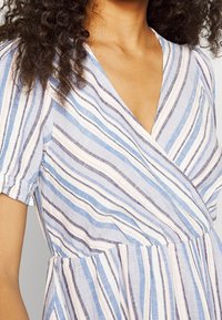 Robe légère rayée en bleu, blanc et rose avec un design portefeuille, des manches courtes et une taille froncée.