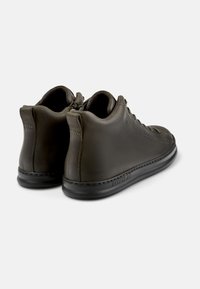 Skórzane wysokie buty w ciemnozielonym kolorze o gładkiej fakturze, wsuwane z przodem na sznurówki oraz kontrastującą czarną gumową podeszwą. Minimalne detale w szwie.