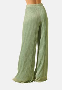 Pantalons larges vert clair en tissu plissé et scintillant, avec une ceinture confortable et une silhouette fluide.